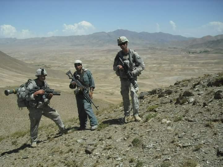 Service members standing in mountainous terrain