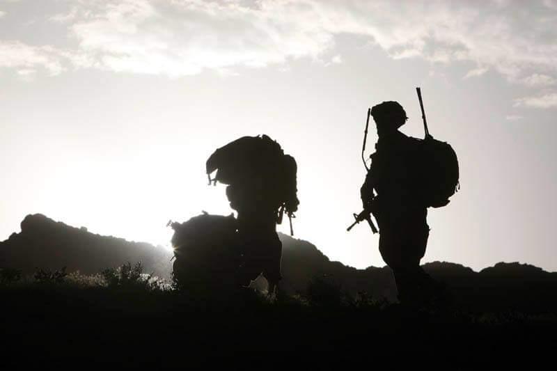 Mountain route with service members moving through open terrain