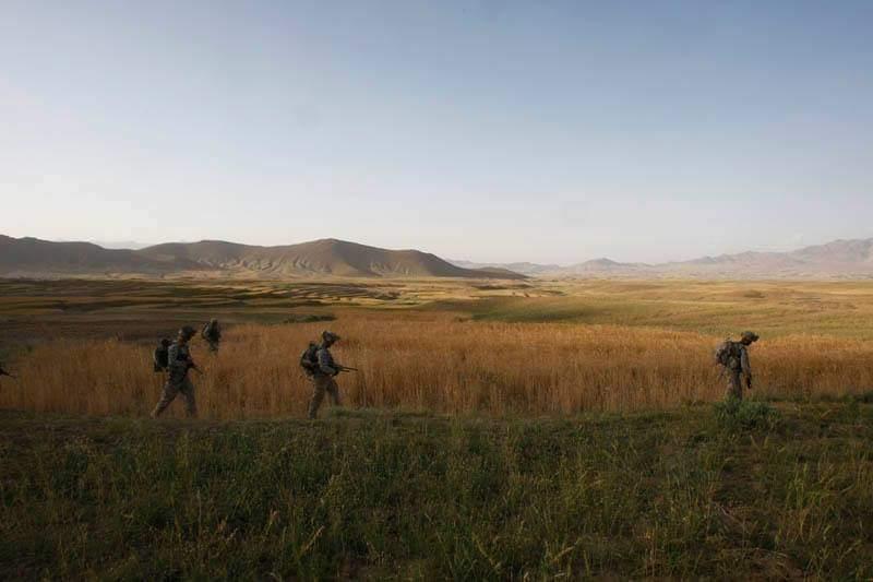 Service members walking across open terrain